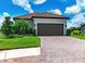 Two-car garage with paver driveway and lush green landscaping at 3134 Francoa Dr, Odessa, FL 33556