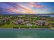 An aerial view of a waterfront condominium community, showcasing a pool, lush lawns, and colorful sunset at 6269 Palma Del Mar S Blvd # 608, St Petersburg, FL 33715