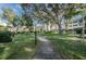 A serene walkway leads to lush green spaces with mature trees, and neighborhood buildings in the background at 1235 S Highland Ave # 2-204, Clearwater, FL 33756