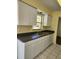 White kitchen cabinets, double sink, and dark countertops at 119 Stafford Dr, Palm Harbor, FL 34684