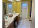 Large bathroom featuring a double sink vanity, white tile floors, and a separate door to the outside at 4922 Lake Valencia W Blvd, Palm Harbor, FL 34684