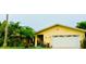 Bright yellow house with a white garage door and tropical landscaping at 1964 Arvis E Cir, Clearwater, FL 33764