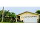 Front view of a charming yellow house with a white garage door and lush landscaping at 1964 Arvis E Cir, Clearwater, FL 33764