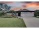 Single-story home with white exterior, landscaped yard, and a two-car garage at 2098 Swan Ln, Safety Harbor, FL 34695