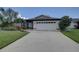 White one-story house with a brown roof, two-car garage, and landscaped front yard at 2098 Swan Ln, Safety Harbor, FL 34695