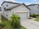 View of a home's two-car garage with gray exterior walls, and adjacent landscaping for curb appeal at 12235 Creek Preserve Dr, Riverview, FL 33579