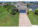 Two-story home with landscaped yard, paver driveway, and palm trees at 879 De Soto Way, Tarpon Springs, FL 34689