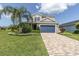 Two story home with a blue garage door and landscaped yard at 879 De Soto Way, Tarpon Springs, FL 34689