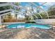 In-ground pool with brick pavers, surrounded by greenery, and an enclosed patio at 1549 Linwood Dr, Clearwater, FL 33755