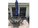 Close-up of a charming patio setting with a round metal table, chairs, and a blue umbrella at 1172 Chelsea Ln, Holiday, FL 34691