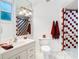 Well-lit bathroom with red patterned shower, a vanity, and a toilet at 2570 Gary Cir # 3, Dunedin, FL 34698