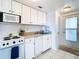 Cozy kitchen featuring white cabinetry, appliances, and tile flooring at 2570 Gary Cir # 3, Dunedin, FL 34698