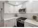 Modern kitchen with white shaker cabinets, quartz countertops, and stainless steel appliances at 1995 Arvis E Cir, Clearwater, FL 33764