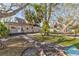 Charming backyard with a fire pit, a lush lawn, mature trees, and a gray house with a walkway in the background at 4132 4Th S St, St Petersburg, FL 33705