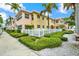 Two-story building with pastel facade, white picket fence, and lush landscaping at 19417 Gulf Blvd # B208, Indian Rocks Beach, FL 33785