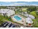 Aerial view of community pool, surrounded by lounge chairs, landscaping, and a nearby pond at 2085 Hunters Glen Dr # 213, Dunedin, FL 34698