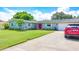 Ranch-style home with a red car parked in the driveway at 1847 Oak Lake Dr, Clearwater, FL 33764