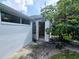 Back exterior view of house with open door and lush landscaping at 8356 Candlewood Rd # 0, Seminole, FL 33777