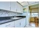 White kitchen with granite countertops and mosaic backsplash at 1893 Shore S Dr # 206, South Pasadena, FL 33707