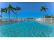 Inviting community swimming pool with palm trees and a bright blue sky at 1893 Shore S Dr # 206, South Pasadena, FL 33707