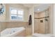 Bathroom with a soaking tub and walk-in shower, featuring neutral tile, and a window at 435 Westwinds Drive, Palm Harbor, FL 34683