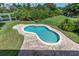 Aerial view of private kidney-shaped pool with a brick paver pool deck and well-maintained landscaping at 435 Westwinds Drive, Palm Harbor, FL 34683