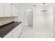 Spacious kitchen with a view towards a hallway with white tile floor and a white decorative hanging light at 3332 Mcmath Dr, Palm Harbor, FL 34684