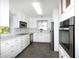White kitchen with stainless steel appliances and herringbone floors at 17734 1St E St, Redington Shores, FL 33708