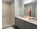Bathroom with double vanity, shower, and gray cabinets at 5930 Precious View Ct, New Port Richey, FL 34655