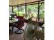 View of a tile-floored screened porch featuring outdoor dining set and glimpses of lush greenery and landscaping at 8210 Valley Stream Ln, Hudson, FL 34667