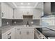 Modern kitchen with white cabinets, stainless steel appliances, and gray backsplash at 4321 Tahitian Gardens Cir # A, Holiday, FL 34691