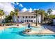 Upscale community pool surrounded by lounge chairs, palm trees, and a bright clubhouse at 19395 Sheltered Hill Dr, Brooksville, FL 34601