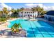 Luxurious community pool surrounded by palm trees, lounge chairs, and an elegant clubhouse at 19395 Sheltered Hill Dr, Brooksville, FL 34601