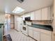 Bright kitchen with white cabinetry, tile backsplash, and modern appliances under a skylight at 10824 Peppertree Ln, Port Richey, FL 34668