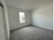 Bright bedroom with grey carpet, neutral walls, and a window at 13447 Newport Shores Dr, Hudson, FL 34669