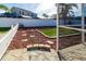 Landscaped backyard with artificial turf, stone pathway, and white fence at 12528 Roseland Dr, New Port Richey, FL 34654