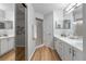 Double vanity bathroom with white cabinets and wood-look floors at 10516 Moshie Ln, San Antonio, FL 33576