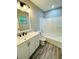 Clean bathroom with white vanity, tub, and wood-look floors at 27173 Simona Ave, Brooksville, FL 34602