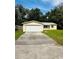 Cute yellow house with a white garage door and a well-maintained lawn at 27173 Simona Ave, Brooksville, FL 34602