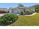 Tan one-story house with a two-car garage, landscaped yard, and walkway at 11654 Holly Ann Dr, New Port Richey, FL 34654