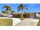 Charming brick home with well-manicured lawn, mature palms, and a spacious driveway under a sunny, blue sky at 12832 3Rd Isle, Hudson, FL 34667