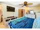 Comfortable main bedroom features a ceiling fan, TV, and a view into an adjacent room at 12832 3Rd Isle, Hudson, FL 34667
