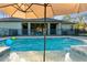 Backyard pool area featuring a waterfall, umbrella, and view of the home's covered patio at 7376 Fall St, Brooksville, FL 34613