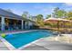 Backyard pool with patio, lounge chairs, and umbrella, perfect for outdoor relaxation and entertainment at 7376 Fall St, Brooksville, FL 34613
