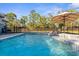 Backyard pool area featuring a tanning deck, umbrella, and view of the fenced in yard at 7376 Fall St, Brooksville, FL 34613