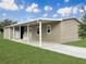 Tan single-story home with covered porch and carport, showcasing a well-maintained lawn at 14287 Rialto Ave, Brooksville, FL 34613