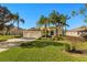 House exterior featuring a three-car garage, lush landscaping, and palm trees at 13235 Legends Trl, Dade City, FL 33525