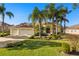 Beautiful home with three-car garage, lush landscaping, and palm trees at 13235 Legends Trl, Dade City, FL 33525