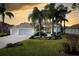 Stunning home exterior at sunset, featuring a three-car garage and manicured lawn at 13235 Legends Trl, Dade City, FL 33525