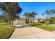 House exterior with a three car garage and driveway, surrounded by palm trees and green grass at 13235 Legends Trl, Dade City, FL 33525